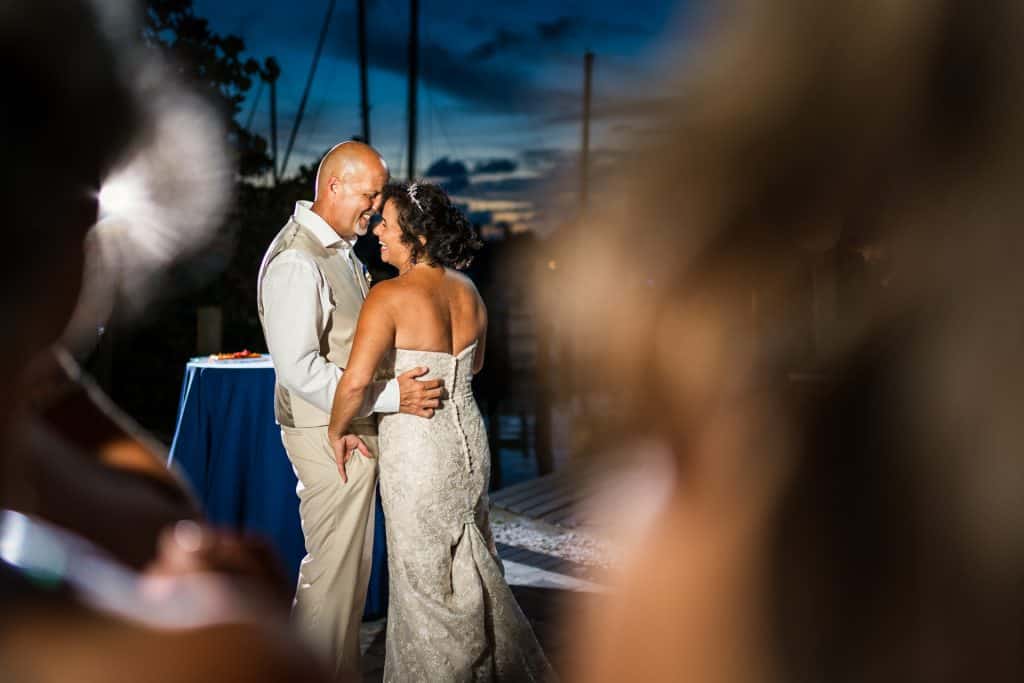 Bride and groom smiling and dancing in the middle of the dance floor outdoors.