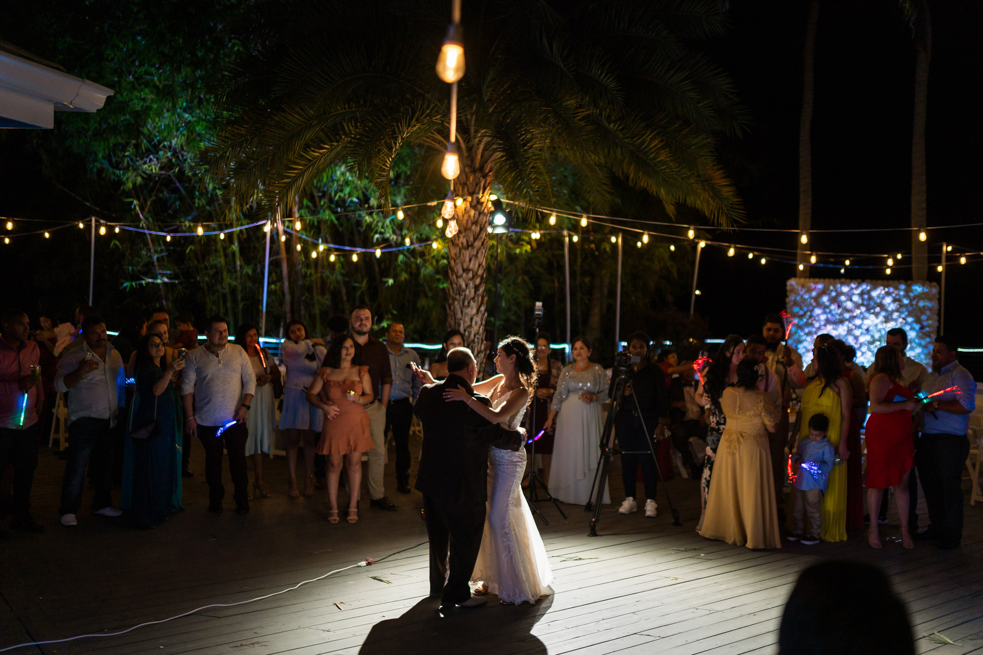 Father and daughter dance during a wedding, outdoors under the moon light.